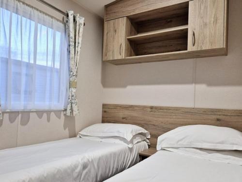 two beds in a room with a window at Birchington Vale - Trieste Sleeps 6 in Westgate-on-Sea