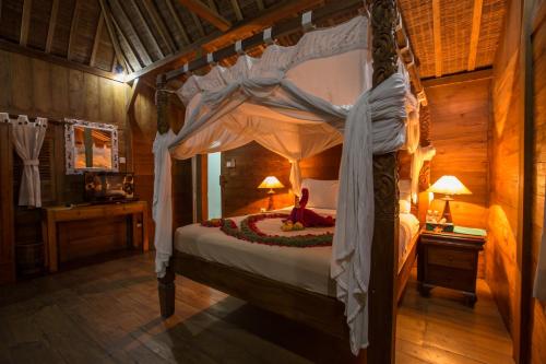a bedroom with a canopy bed with a woman sitting on it at Villa Mandi Resort & spa in Ubud