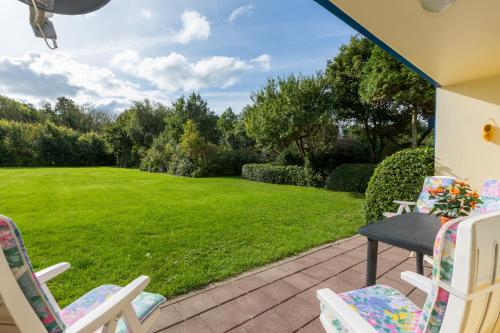 a patio with chairs and a grass yard at Welcome in - Appartement dichtbij het strand, met fietsenberging en ruim terras in Vlissingen