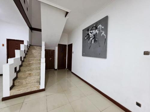 a hallway with stairs and a painting on the wall at Casa Palma by Ezzego in Bandung