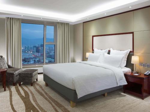 a bedroom with a large bed and a large window at Novotel Ulaanbaatar in Ulaanbaatar