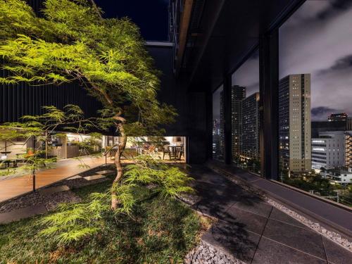 a tree on a balcony with a view of the city at Pullman Tokyo Tamachi in Tokyo