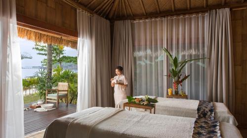 a woman standing in a bedroom with two beds at Montigo Resorts Nongsa in Nongsa