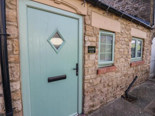 a blue door of a stone building with a window at 2 Low Road in Bishop Auckland