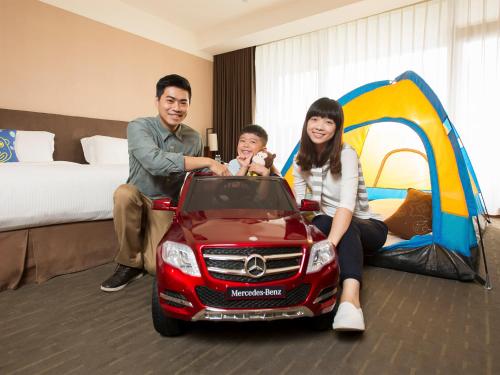 a man and woman with a child in a car in a hotel room at Silks Place Yilan in Yilan City
