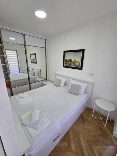 a large white bed in a room with a mirror at Luxury flat Boka Nest in Dobrota