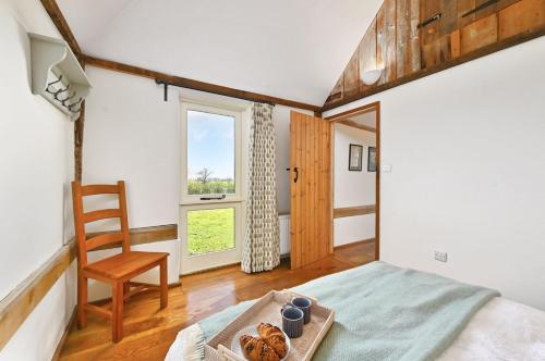 a bedroom with a bed and a chair and a window at Acorn Barn in Ashford