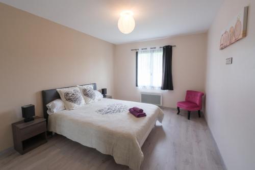 a bedroom with a large bed and a pink chair at Fleur Du Ciel Vendée in Challans