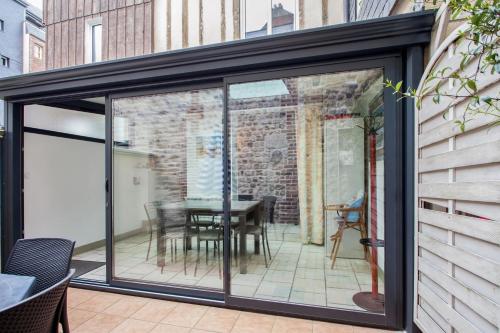 a sliding glass door on a patio with a table at Maison charmante près de Sainte Catherine in Honfleur