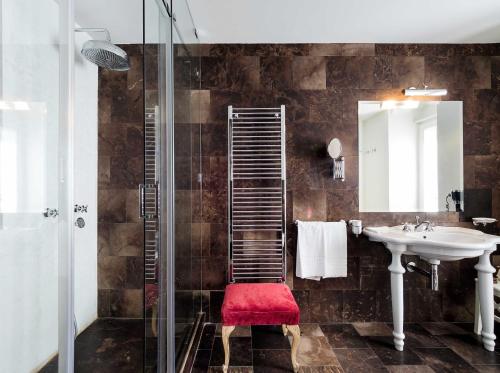 a bathroom with a sink and a shower and a red stool at Gagliardi Boutique Hotel in Noto