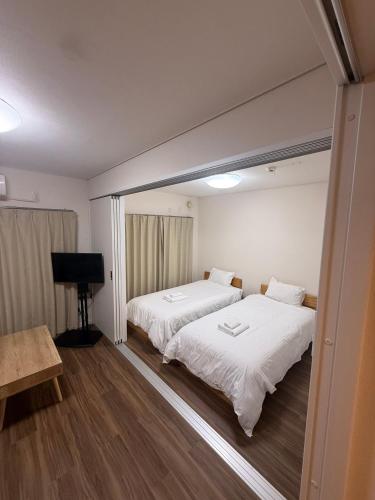 ein Zimmer mit zwei Betten und einem Flachbildfernseher in der Unterkunft casa de sol in Miyakojima