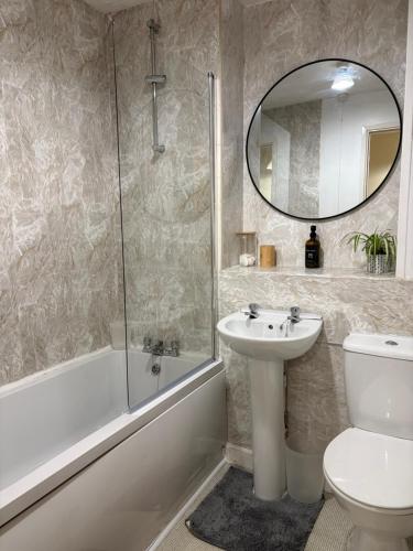 a bathroom with a sink and a toilet and a mirror at Lovely Holiday Home to explore beautiful West Wales in Carmarthen