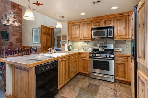 a kitchen with wooden cabinets and a stove top oven at Epic view condo with fireplaces & close to everything in Park City