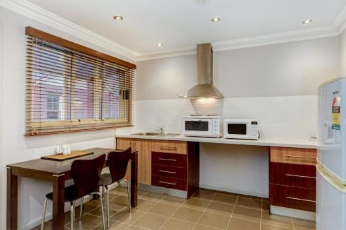 a kitchen with a table and a microwave oven at Seymours On Lydiard in Ballarat
