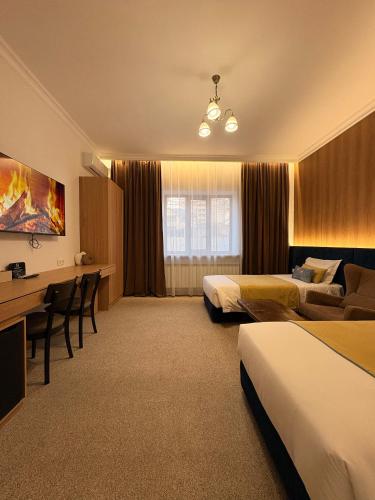 a hotel room with two beds and a desk at Keremet Hotel in Almaty