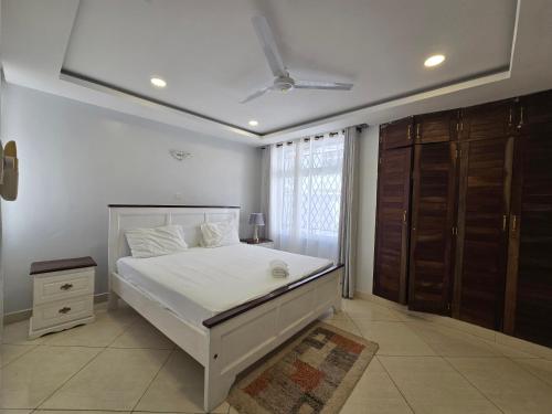 a bedroom with a white bed and a window at Impala Villas in Mombasa