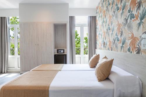 a bedroom with a large bed in a room with windows at Hotel Mediodia in Madrid