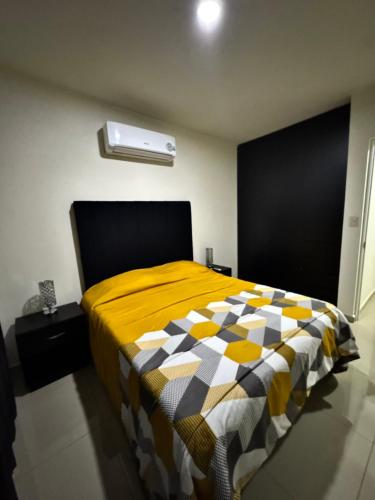a bedroom with a bed with a yellow and white comforter at Casa en Privada! in Culiacán