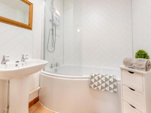 a white bathroom with a tub and a sink at 4 Bed in Llandovery oc-82440 in Llanfair-ar-y-bryn