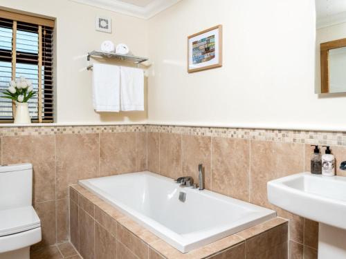 a bathroom with a tub and a sink and a toilet at 4 Bed in Ystradgynlais oc-bn343 in Ystalyfera