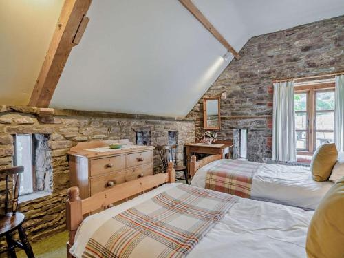 a bedroom with two beds and a stone wall at 2 Bed in Brecon oc-bn281 in Llanhamlach