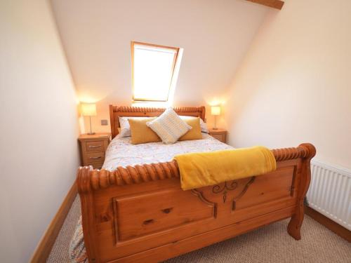 a bedroom with a wooden bed with a yellow blanket on it at 2 Bed in Abergavenny oc-65965 in Pandy