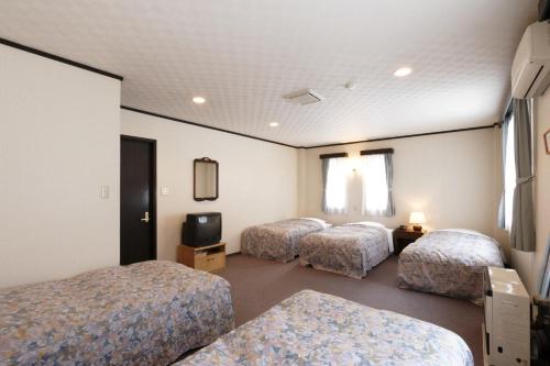 a hotel room with three beds and a tv at Hill Top in Kiso