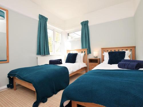 two beds in a bedroom with blue curtains at 4 Bed in Barnstaple oc-73949 in Stoke Rivers