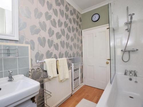 a bathroom with a sink and a bath tub and a clock at 4 Bed in Barnstaple oc-73949 in Stoke Rivers