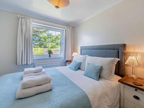 a bedroom with a large bed with white and blue pillows at 2 Bed in Woolacombe oc-bkers in Woolacombe