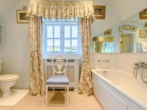 a bathroom with a tub and a chair next to a window at 3 Bed in Presteigne oc-78336 in Evenjobb
