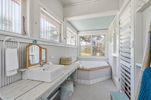 a bathroom with a sink and a tub and windows at Rancho Crescent Head in Crescent Head