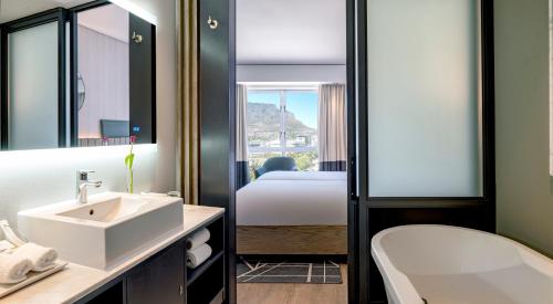 a bathroom with a sink and a tub and a bed at Hyatt Regency Cape Town in Cape Town