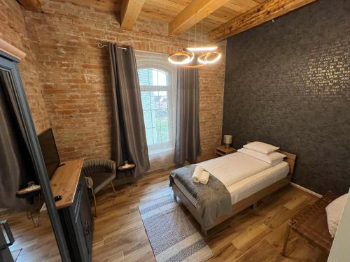 a bedroom with a bed and a desk and a window at Tejmalom Szálló in Sárrétudvari