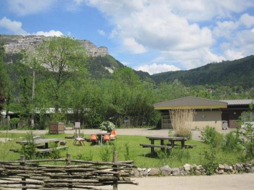 a picnic area with picnic tables and mountains in the background at Camping Le SIGNAL Nantua in Nantua