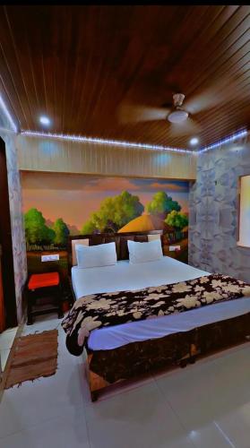 a bedroom with a large bed with a painting on the wall at Hotel Preet La Casa in Thānesar
