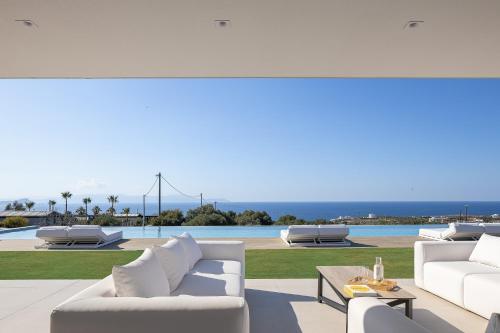 a living room with white furniture and a view of the ocean at Oliva D'oro Villa - Sunset Gaze by etouri in Chania