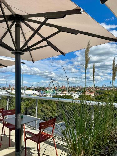 une table et des chaises sous un parasol sur un balcon dans l'établissement Cocoon München Theresienwiese, à Munich