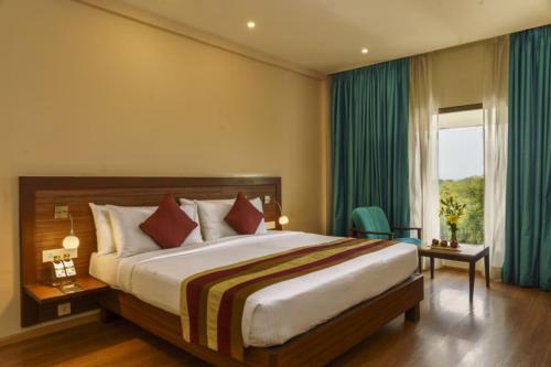 a bedroom with a large bed and a large window at Hotel Tamilnadu Pandiyan Madurai in Madurai