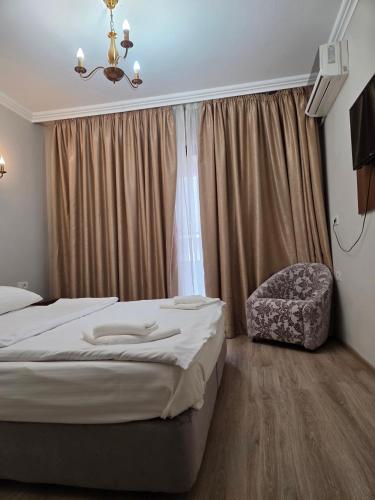 a bedroom with a bed and a chair and a window at Pensiunea La Iani in Constanţa