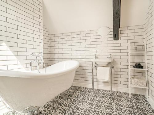 a white bathroom with a tub and a sink at 3 Bed in Brecon oc-92320 in Llandeilor-Fan
