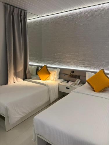 two beds with yellow pillows in a room at HYVE Siliguri in Siliguri