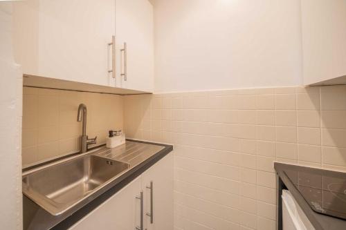 a kitchen with a stainless steel sink and white cabinets at Cozy Studio A C 2P - Saint-Tropez in Saint-Tropez
