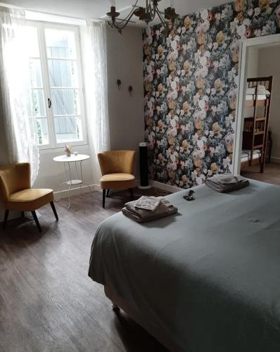 a bedroom with a bed and a wall of flowers at La P'tite Place in Les Arques