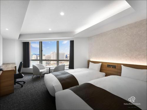 a hotel room with two beds and a desk at Daiwa Roynet Hotel Nagoya Eki Mae in Nagoya