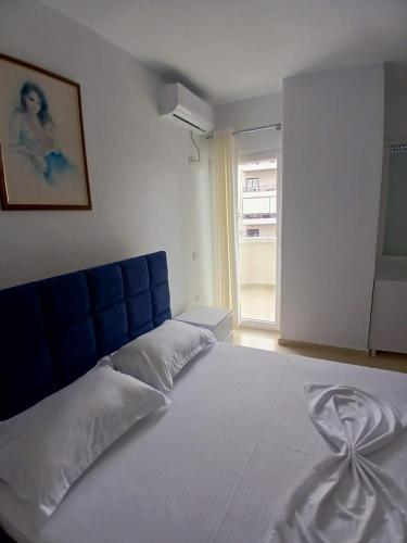 a bedroom with a large white bed with a blue headboard at Amaris-Kian Tragaj Apparent in Vlorë