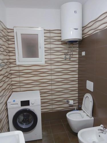 a bathroom with a washing machine and a toilet at Amaris-Kian Tragaj Apparent in Vlorë