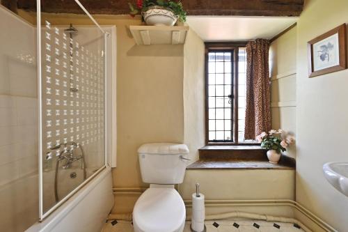 a bathroom with a toilet and a sink and a window at The William Penn At Wickham Manor in Winchelsea