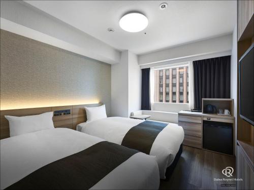 a hotel room with two beds and a television at Daiwa Roynet Hotel Nagoya Eki Mae in Nagoya