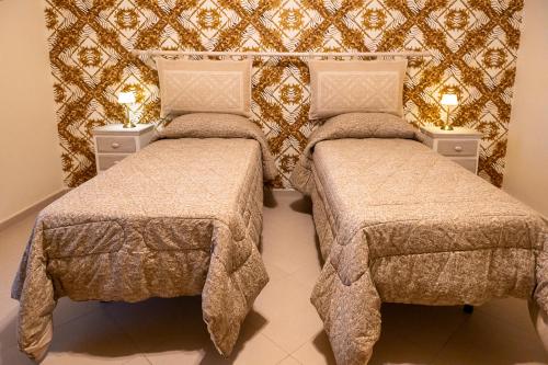 two beds in a room with a wall at Alloggio Turistico Porta di Poggio in Tuscania